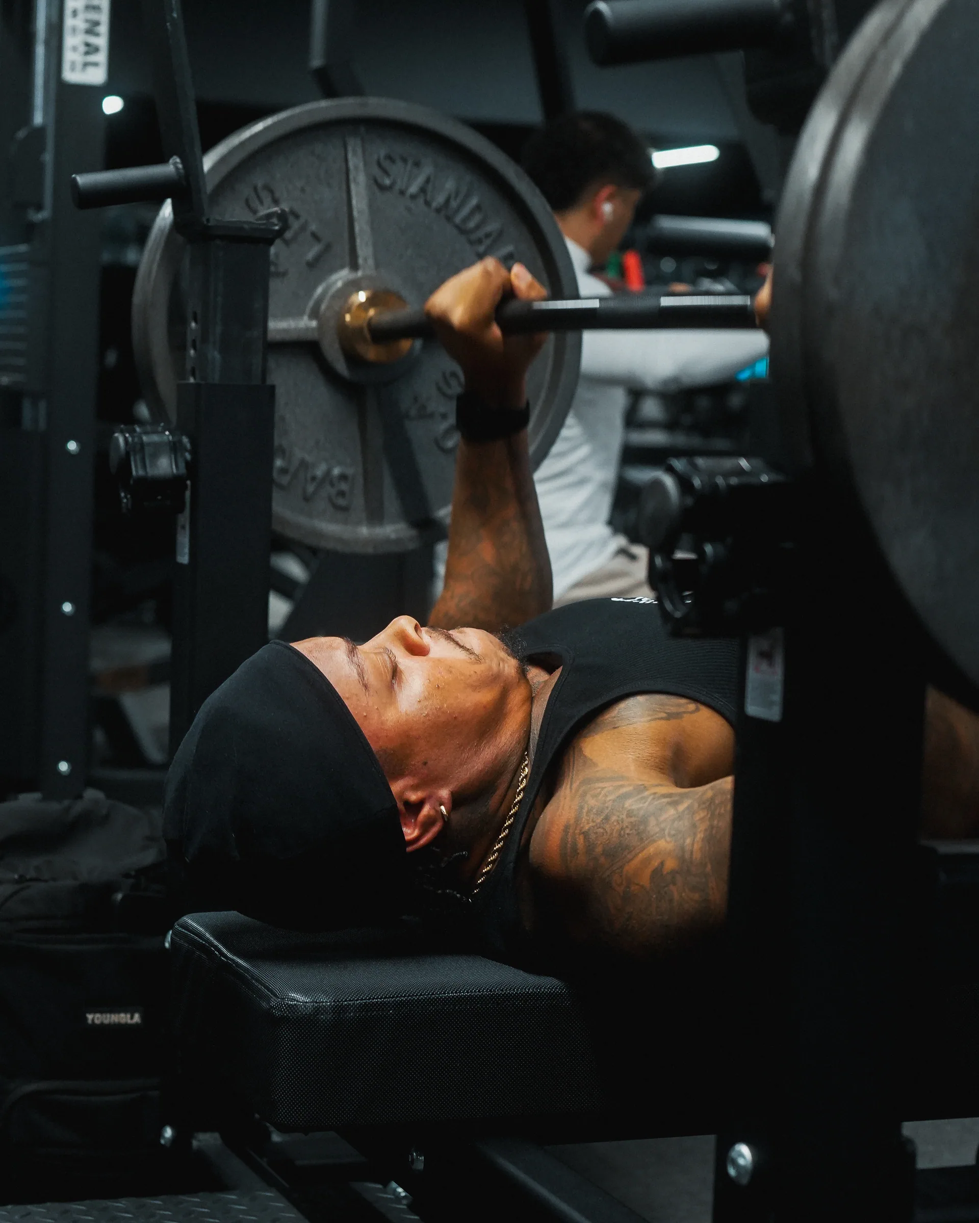 A member pressing a heavy bench with a spotter standing over the bar.