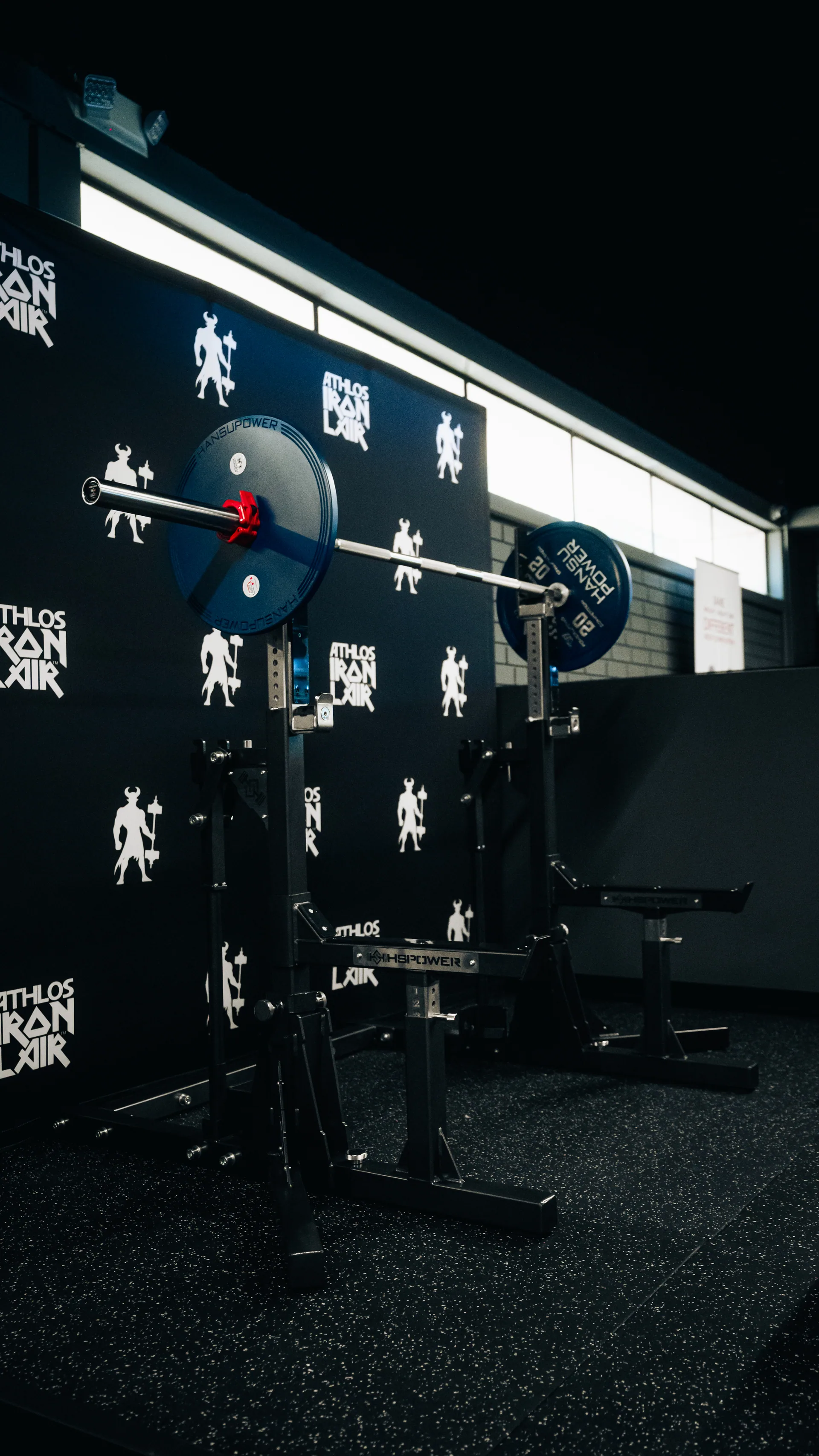 Barbell rack against the branded wall, logo decals behind it