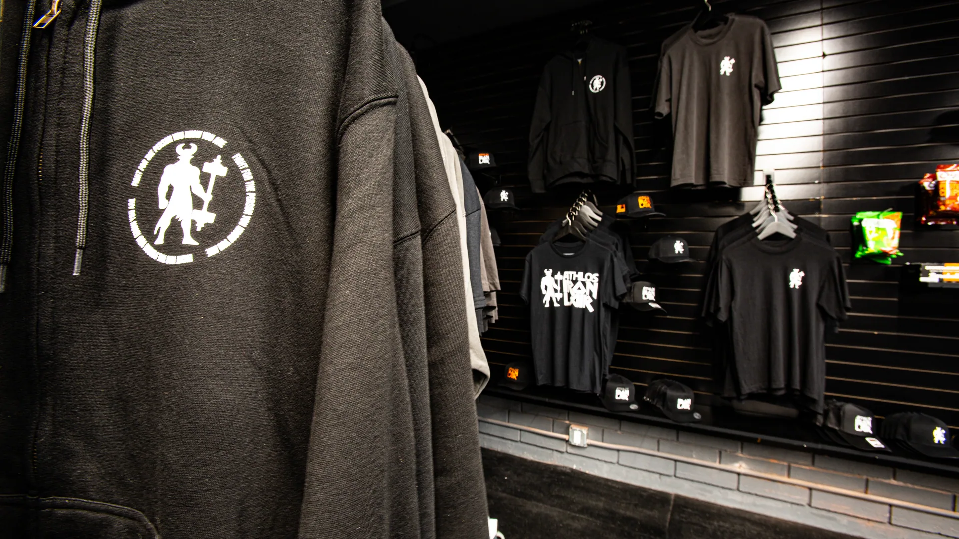 Branded Athlos Iron Lair hoodies and shirts on the merchandise wall